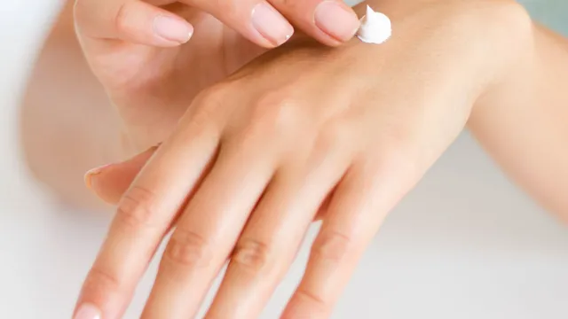 A person applying moisturizing cream to the back of their hand