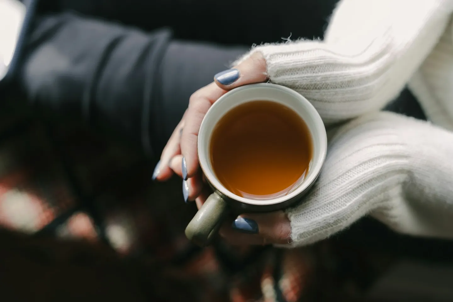 A woman's hands wrapped around a warm cup of tea, resting calmly
