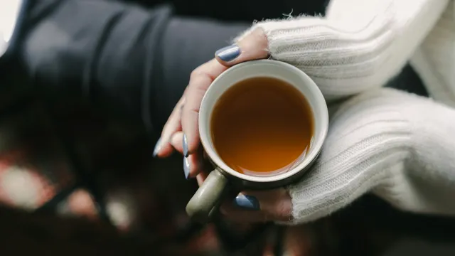 A woman's hands wrapped around a warm cup of tea, resting calmly