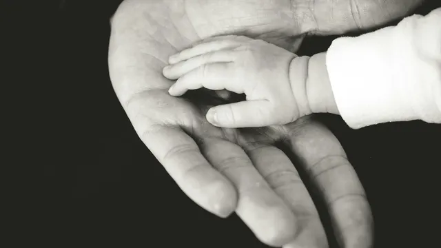 A young child's hand resting in a parent's open hand