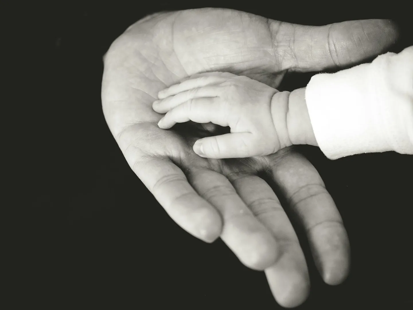 A young child's hand resting in a parent's open hand