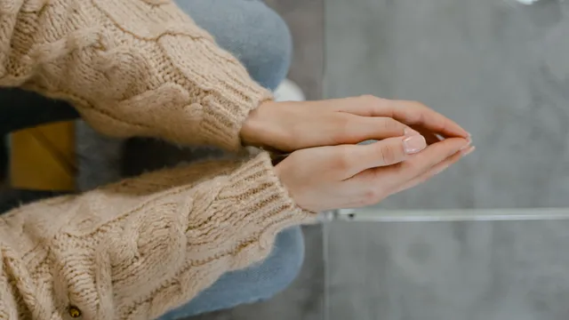Close-up of a person's clasped hands resting in their lap