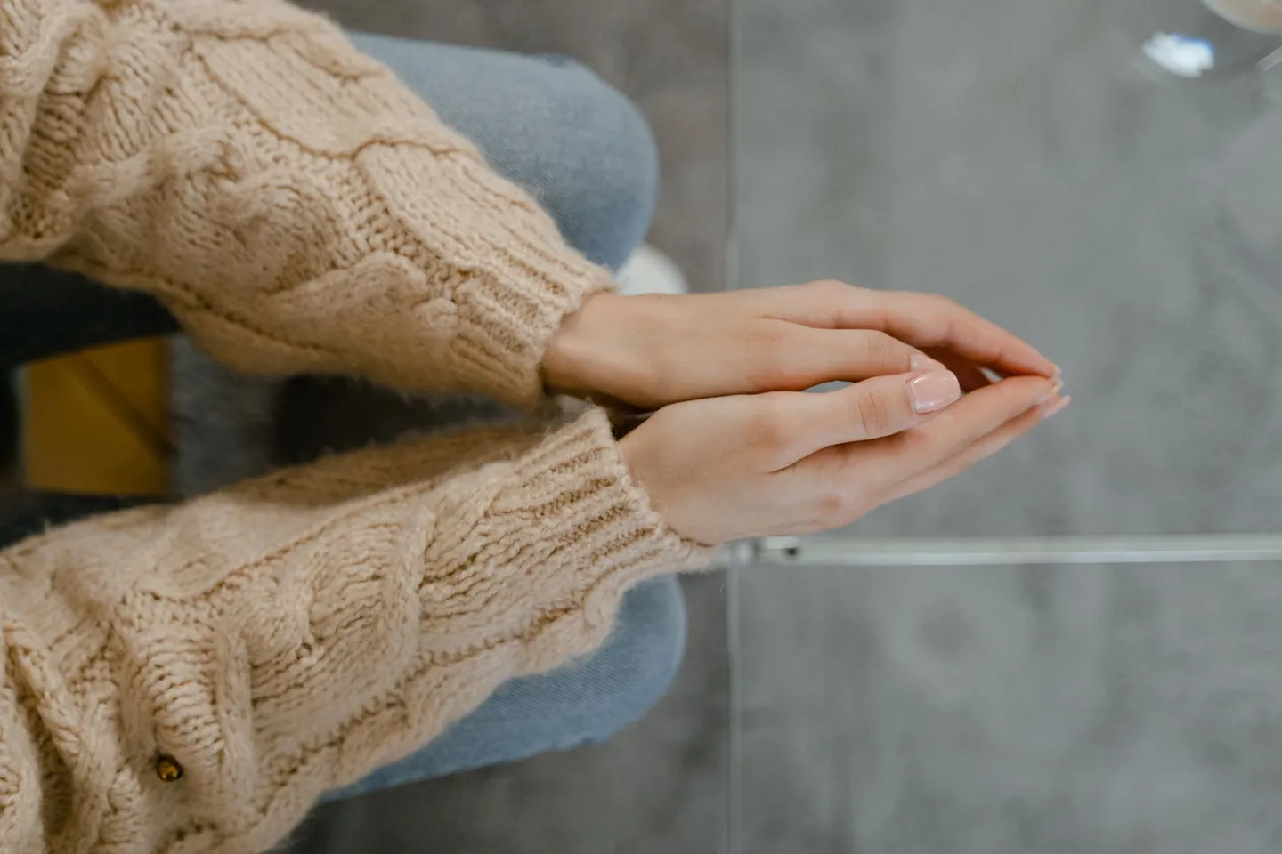Close-up of a person's clasped hands resting in their lap