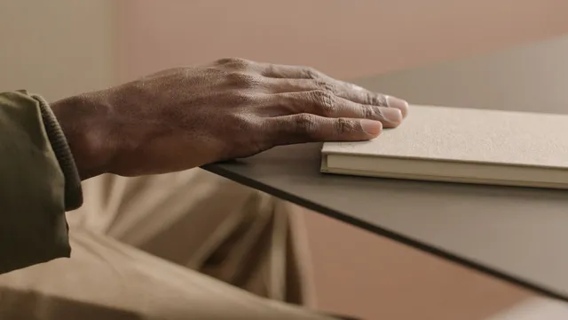 Close-up of a hand resting calmly on a beige notebook on a table
