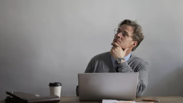 Person resting their chin on their hand while working at a laptop
