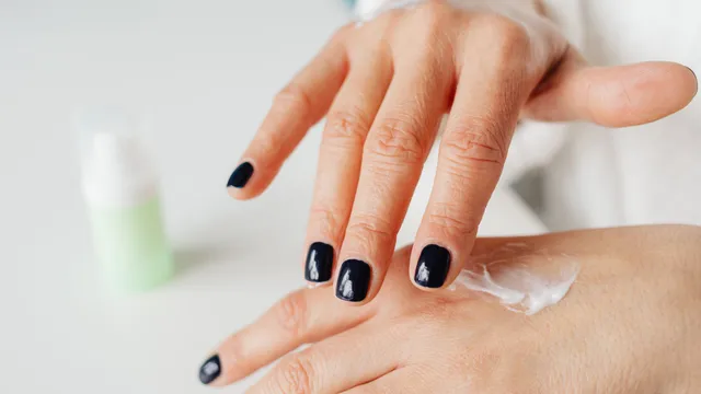 Close-up of hands gently applying cream to the skin