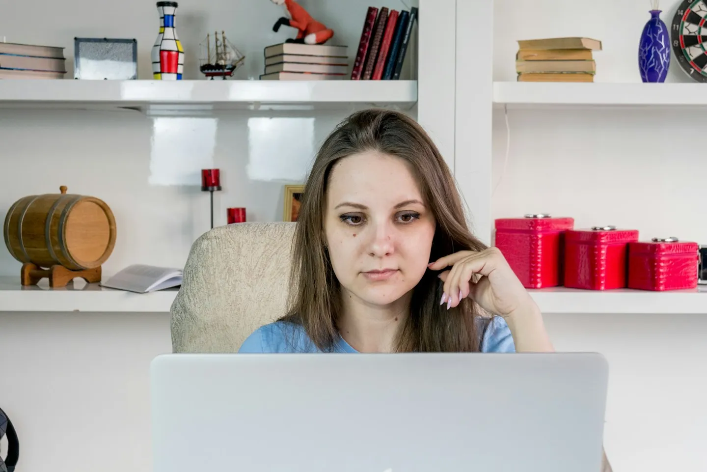 Woman sitting at a laptop, gazing away from the screen, lost in thought