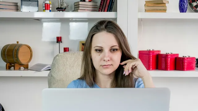 Woman sitting at a laptop, gazing away from the screen, lost in thought