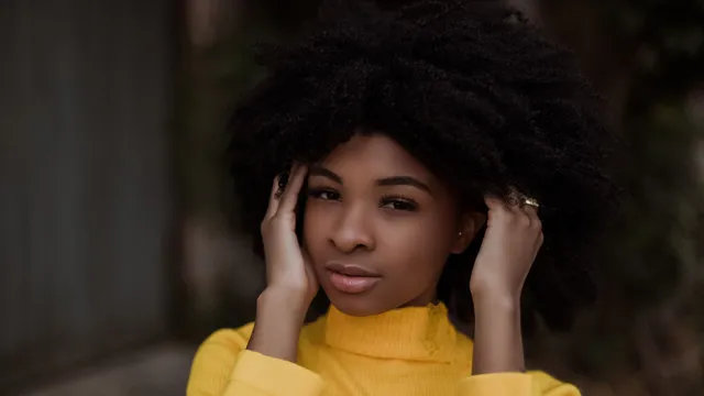 Young woman touching her curly hair while standing outdoors
