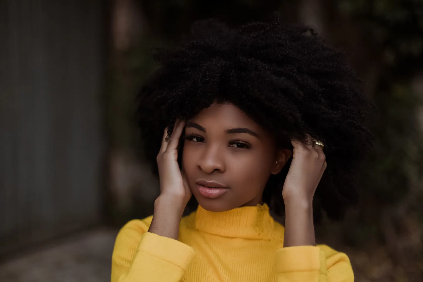 Young woman touching her curly hair while standing outdoors